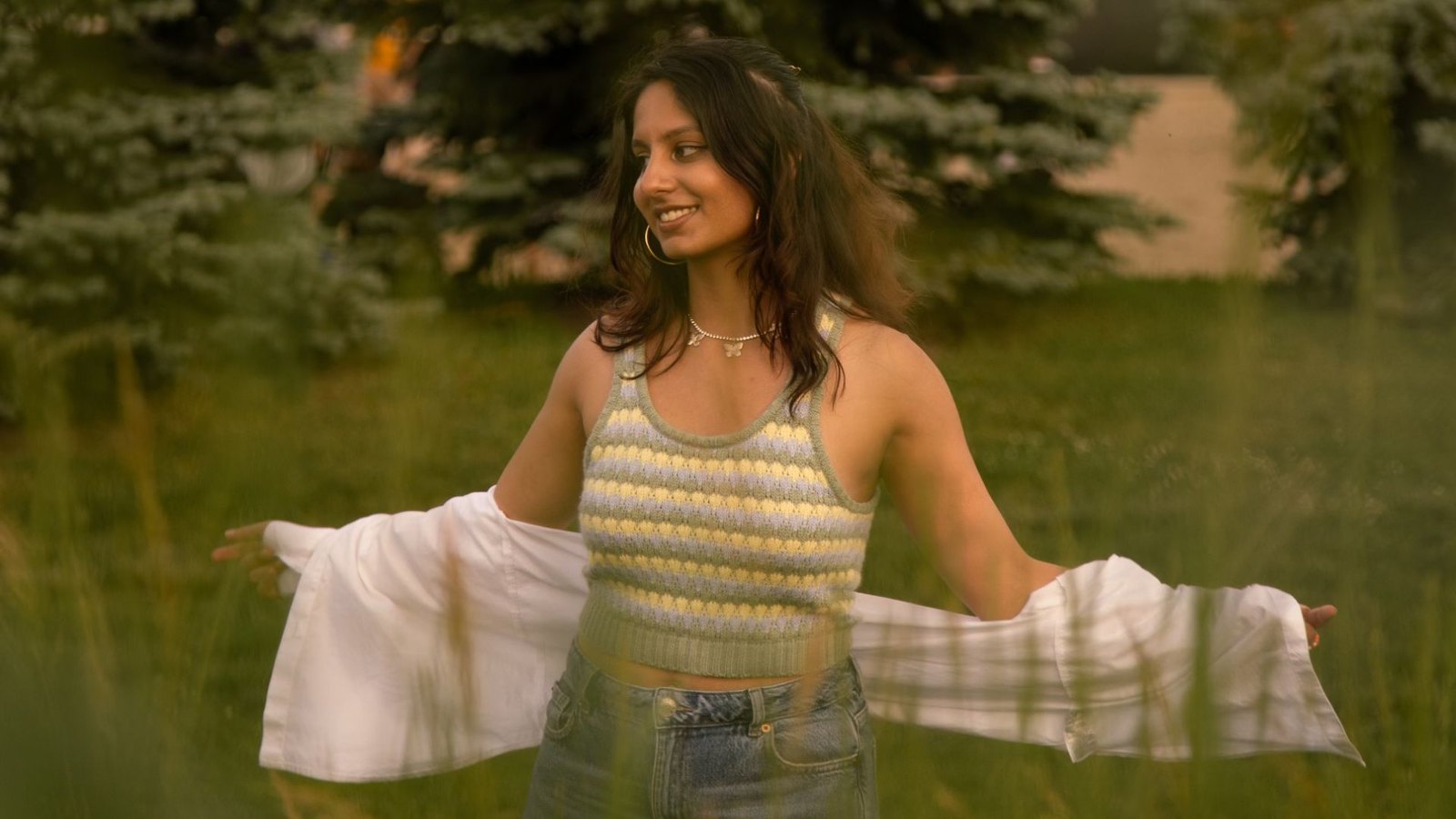 Riha at golden hour in a field, arms open